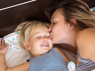 Wall Mural - Happy mother kissing her little son.