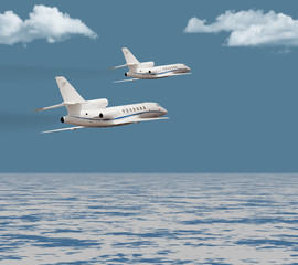 Two private jets flying over the ocean