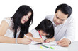 © Creativa Images - Child write on the book with her parents