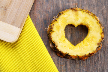 Poster - Pineapple slice with cut in shape of heart on wooden background