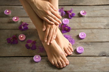 Canvas Print - Female feet at spa pedicure procedure with flowers and candlelight on wooden background