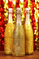 Poster - Decorated champagne bottles on bright sparkling blurred background