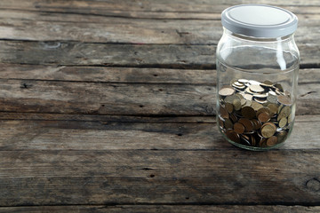 Sticker - Coins in money jar on wooden background