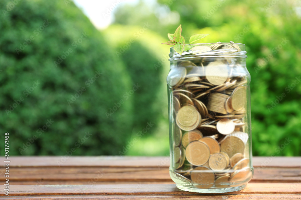 Coins in money jar on table outdoors