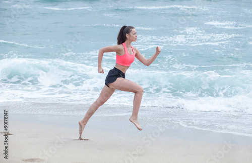 Leinwand Poster woman running on the beach at cloudy morning, side view