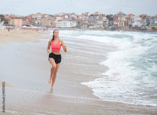 young sporty woman runs along the coastline at the morning Fototapete