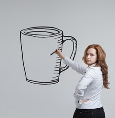 young woman draws a Cup of coffee on grey background