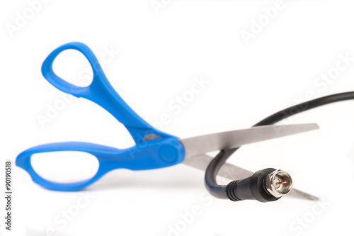 Fotografie, Obraz Scissors cutting through a coaxial RG6 cable - cut the cable tv concept isolated