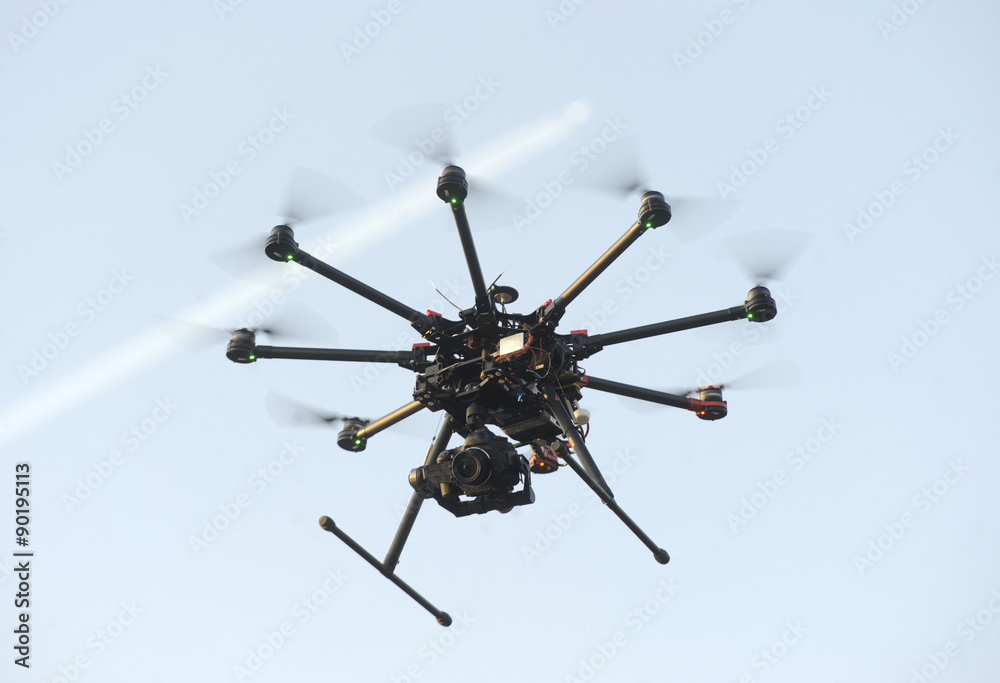 A drone with a camera flying high above a residential area - obrazy, fototapety, plakaty 