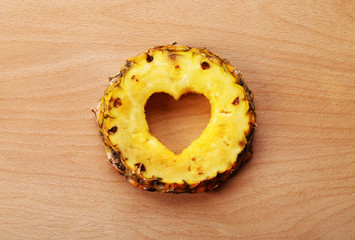 Poster - Pineapple slice with cut in shape of heart on wooden background