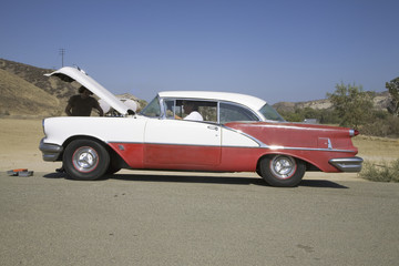 1954 red & white Oldsmobile with hood up and two males stranded after breakdown, near Santa Paula, California, off Highway 126