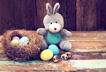 Wall Mural - Vintage Easter eggs colorful with bunny doll on wood table, instagram filter