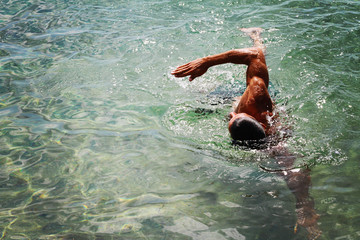 Strong muscular man swimming in the sea ocean scrawl style. Active summer holiday vacation. Sport, healthy lifestyle concept