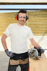 Wall Mural - handsome young man carpenter working with electric tool on wood timber in construction site