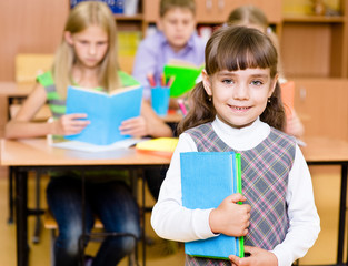 Fototapete - portrait of pretty preschool girl with books in classroom
