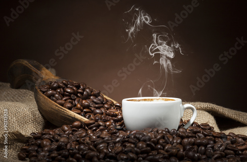 Fototapeta na wymiar White cup with coffee beans on dark background