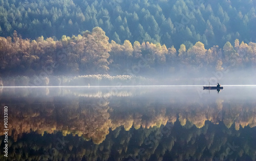 Fotografía One angler fishing on a misty lake.