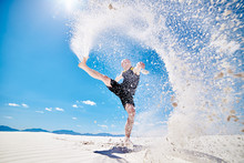 Action Photo Of Man Kicking Huge Trail Of Sand Into The Air While Doing Martial Arts