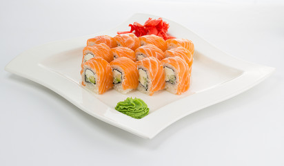 Salmon (philadelphia) sushi roll on a white plate with ginger and wasabi