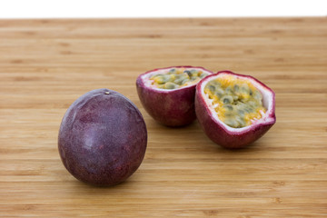 Wall Mural - Close-up of a whole and split passion fruits (passionfruit, purple granadilla (Passiflora edulis)) on a wooden table.