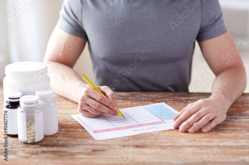 Fotografia close up of man with protein jars and diet plan
