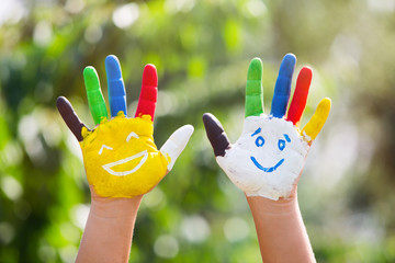 Colored hands with smile painted in colorful paints against gree