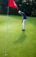 a man with a cap playing golf on a green field