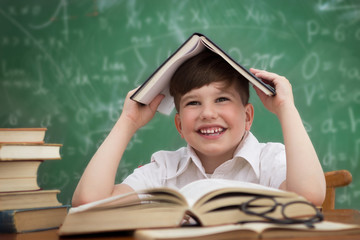 Wall Mural - Happy little boy, pupil with book on head