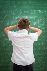 Wall Mural - Upset child looking at blackboard full of formulas