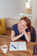 © contrastwerkstatt - entspannte frau sitzt zuhause am tisch und schreibt etwas auf