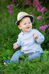 Wall Mural - Toddler sitting on the grass in a meadow. A baby on the background