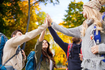 Wall Mural - group of smiling friends with backpacks hiking