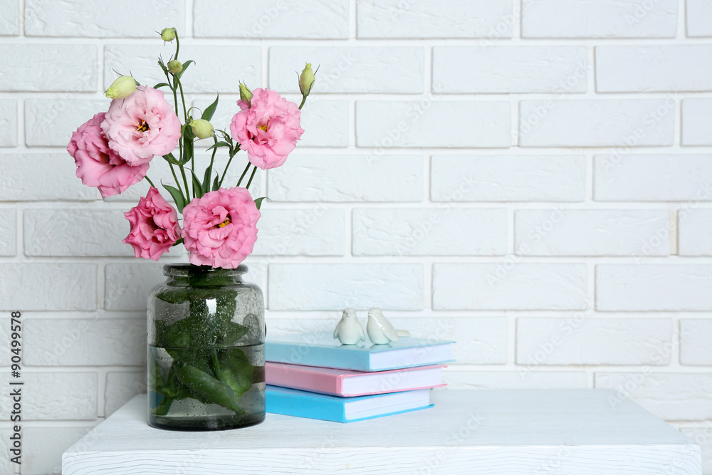 Beautiful flowers with books on brick wall background