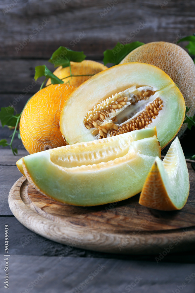 Ripe melons with green leaves on wooden table close up
