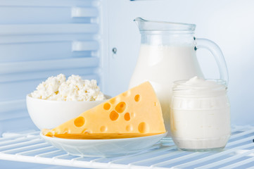 tasty healthy dairy products in the refrigerator: sour cream in the bank, cottage cheese in  bowl,  cheese  and milk in a jar