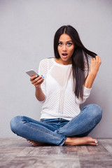 Wall Mural - Woman sitting on the floor with smartphone