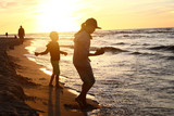 Fototapeta Fototapety z morzem do Twojej sypialni - Wakacje nad morzem. Dzieci bawią się na brzegu morza podczas zachodu słońca