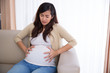 © Odua Images - Asian pregnant woman has stomachache sitting on her couch