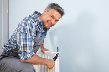 Happy Plumber Fixing Radiator