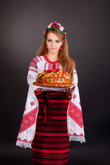 Wall Mural - Young woman in ukrainian clothes, with garland and round loaf