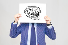 Business Man Hoding Card With Troll Face On Grey Background