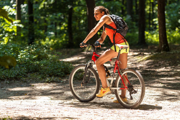 Gracefully biking through the forest, a skilled female athlete enjoys the mountain bike ride.