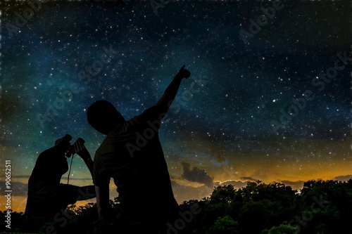 Cuadros en Lienzo Silueta de hombre adulto observa cielo nocturno con el niño.