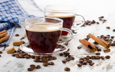 Two Glass Coffee cups and beans on a wooden background.