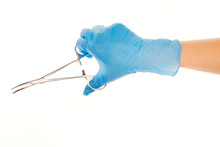 Close Up Of Female Doctor's Hand In Blue Sterilized Surgical Glove With Forceps Against White Background