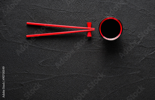 Foto Chopsticks and bowl with soy sauce on black stone background