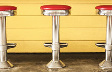 Three Retro Chrome Diner Stools.  Red Vinyl Seats, Yellow Background