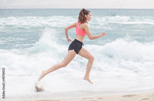 Foto attractive sporty woman running along the beach