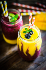 Wall Mural - Colorful two layer smoothies with mango and berries on rustic wo