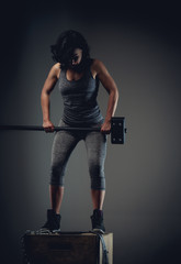 Wall Mural - Sporty woman in grey sportswear standing on wooden box.